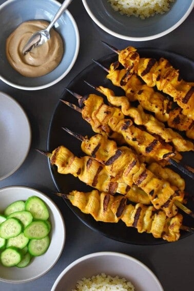 An overhead shot of Chicken Satay and Hoisin No-Nut Sauce along with some sliced cucumbers and cauliflower rice.