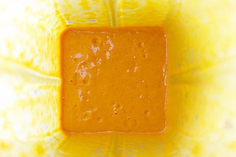 An overhead shot of the finished bright orange chicken satay marinade in the blender.