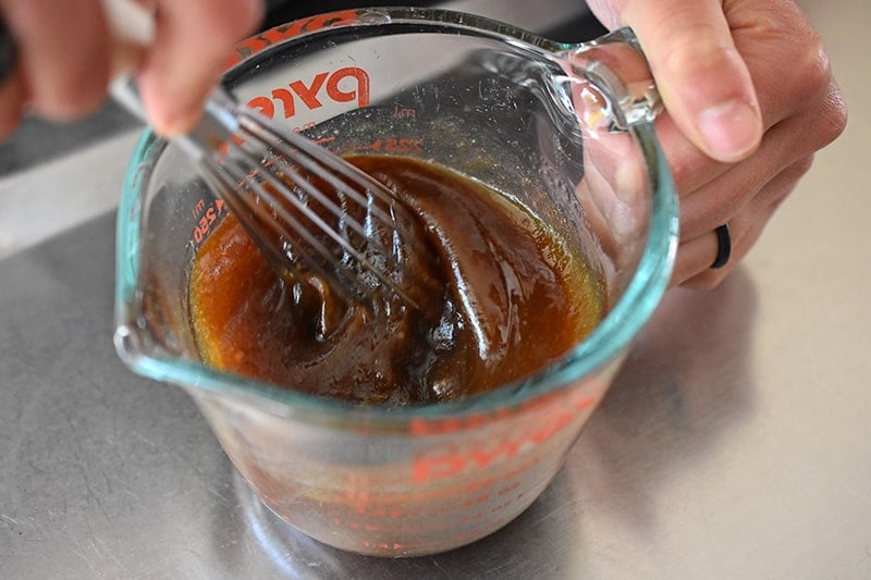 An overhead shot of someone whisking All-Purpose Stir-Fry Sauce with avocado oil to make a Whole30 salad dressing.
