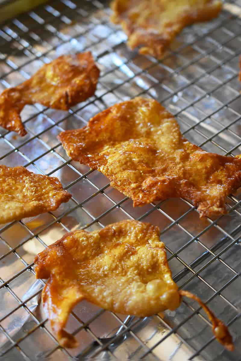 A tray of crispy chicken skin chips cooling on a wire rack.