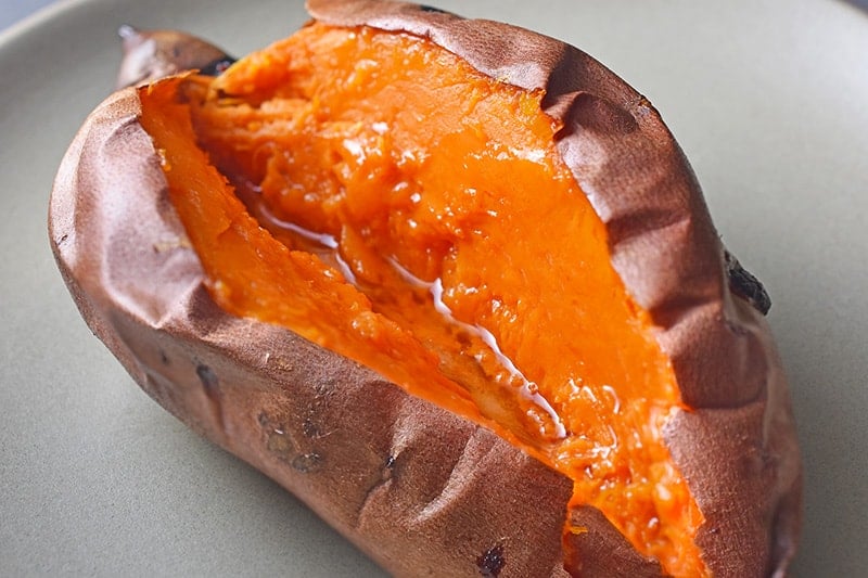 A baked sweet potato split in half with melted ghee.