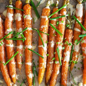 An overhead shot of air fryer roasted carrots topped with ginger sesame dressing and fresh chives.