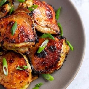 An overhead shot of a platter of Asian Chicken Thighs topped with sliced scallions.