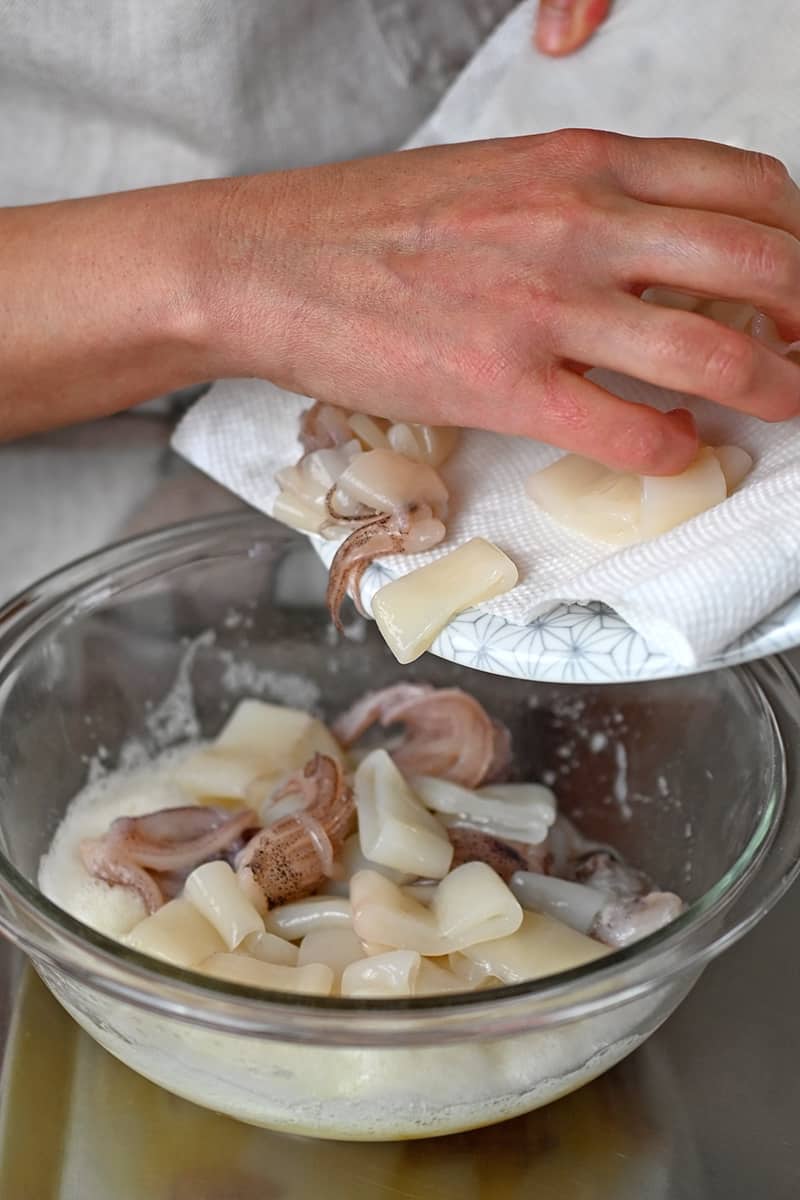 Adding the calamari to a bowl filled with whisked egg whites