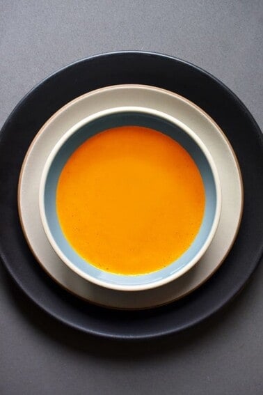 An overhead shot of Carrot Cardamom soup in a serving bowl.