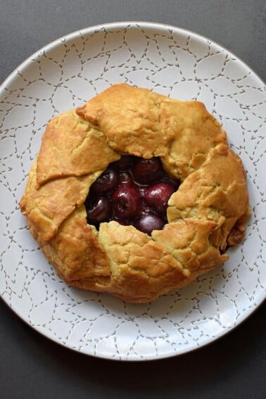 An overhead shot of paleo and gluten-free cherry galette on a white plate
