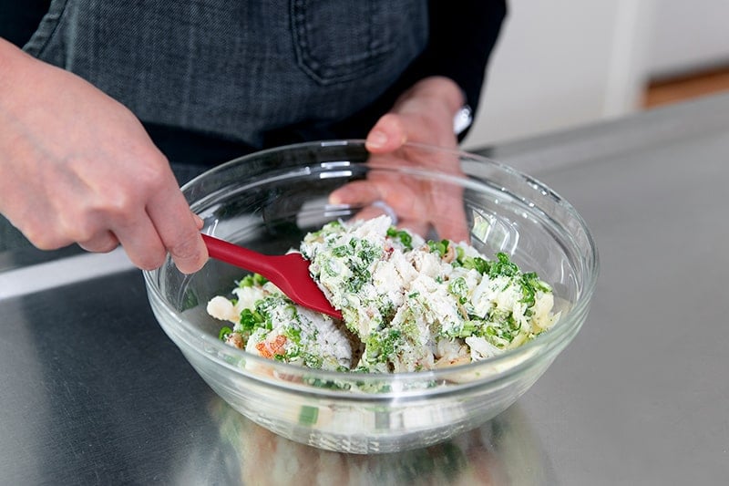 Mixing the paleo crab cake mixture with a red silicone spatula.
