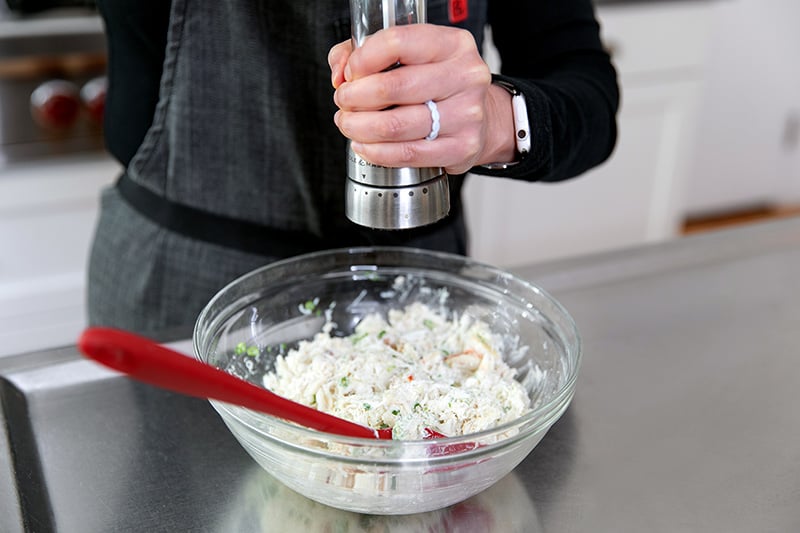 Cracking fresh black pepper on the paleo crab cake mixture.