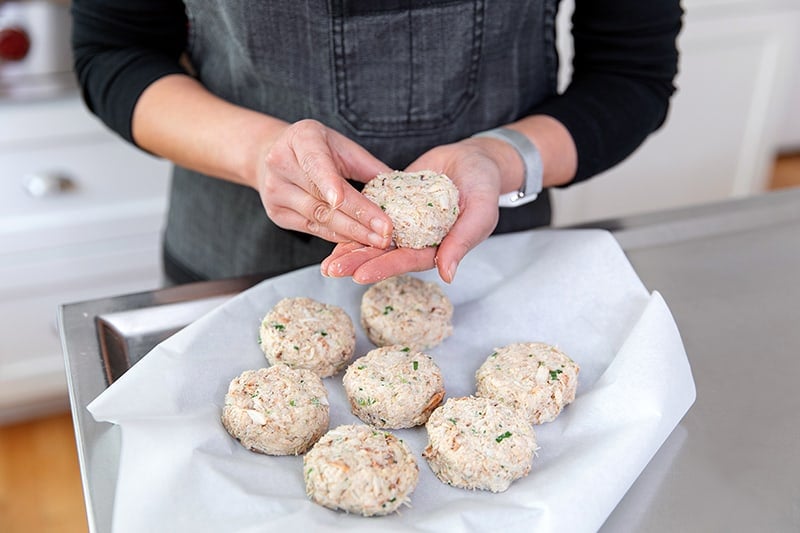 Forming gluten-free and keto crab cakes on a parchment paper lined plate.