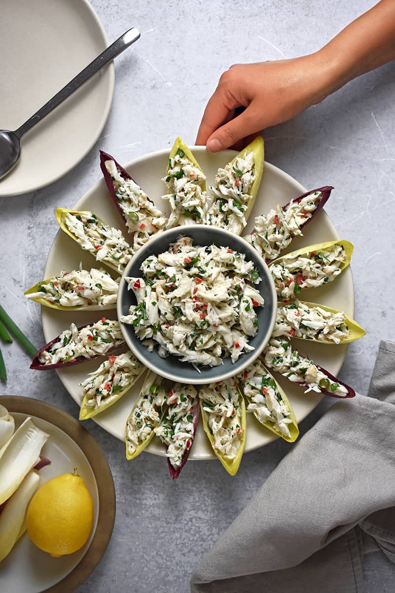 An overhead shot of a platter of endive spears filled with simple crab salad