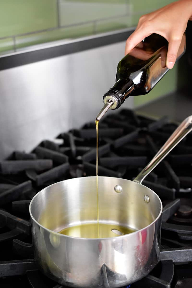 Pouring olive oil into a large saucepan to make cream of tomato soup