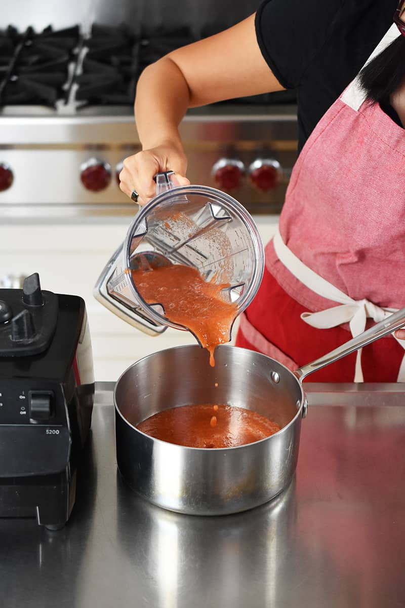 Pouring blended diced tomatoes into a saucepan
