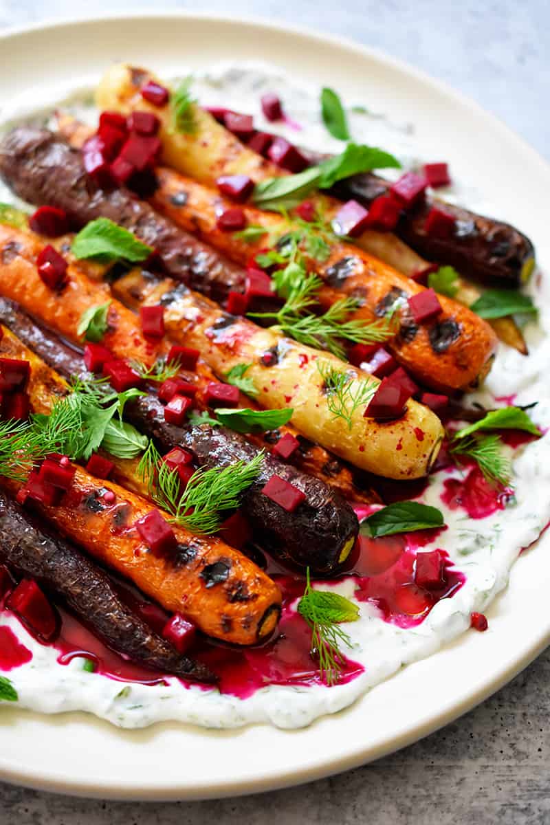 A closeup side shot of Grilled Carrots with Herby Coconut Yogurt and a spicy beet vinaigrette