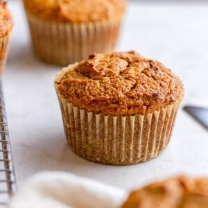 Three paleo pumpkin muffins are on a marble counter top.