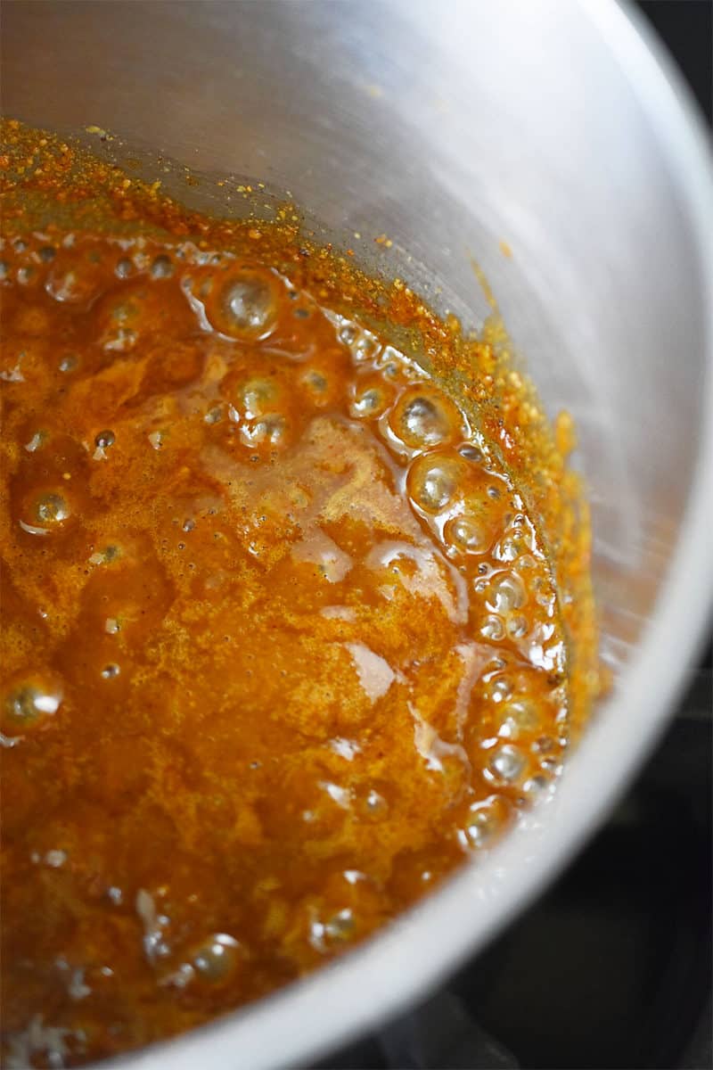 A closeup shot of paleo hoisin sauce simmering in a small stainless steel saucepan
