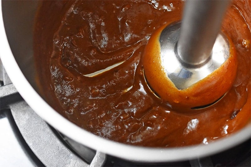 Using an immersion blender in the the saucepan to make the paleo hoisin sauce smooth.