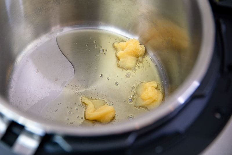 An overhead shot of an open Instant Pot with ghee melting inside.