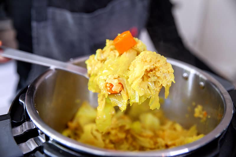 Scooping out a spoonful of Instant Pot Atakilt Wat, Ethiopian cabbage stew.