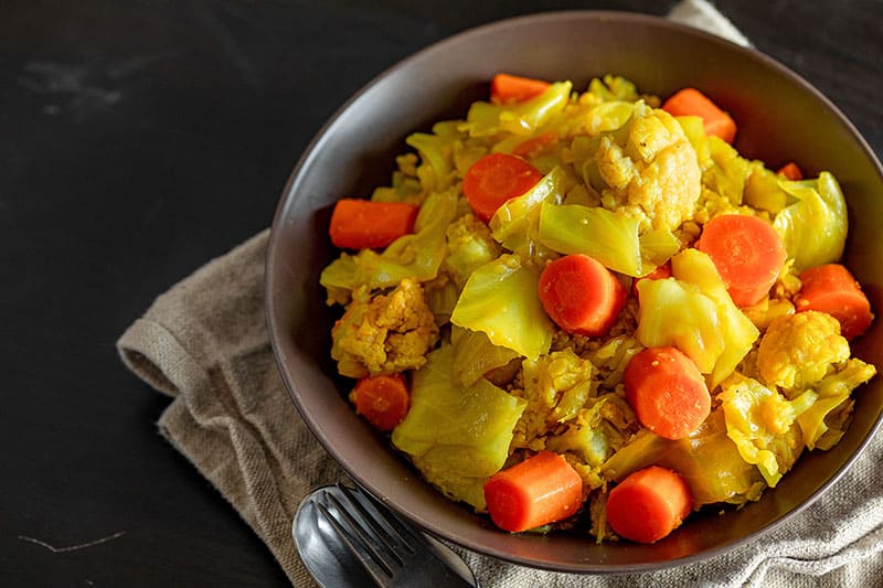 An overhead shot of a brown bowl filled with Whole30 and low carb Atakilt Wat, Ethiopian cabbage stew.