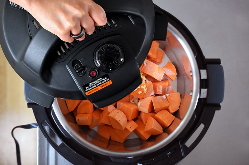 Putting the lid on an Instant Pot to cook mashed sweet potatoes.