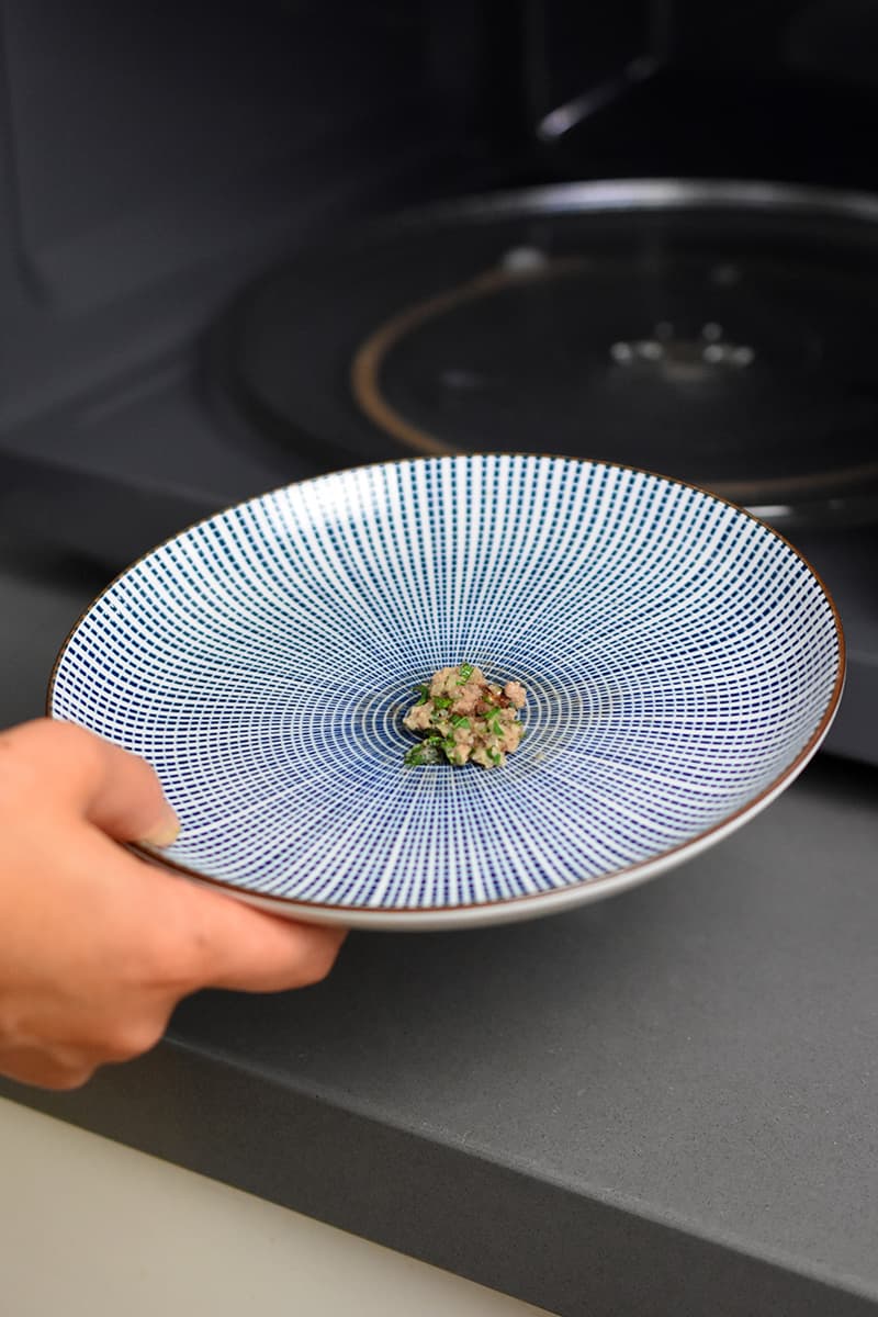 A small patty of cooked meatball meat on a blue and white plate.