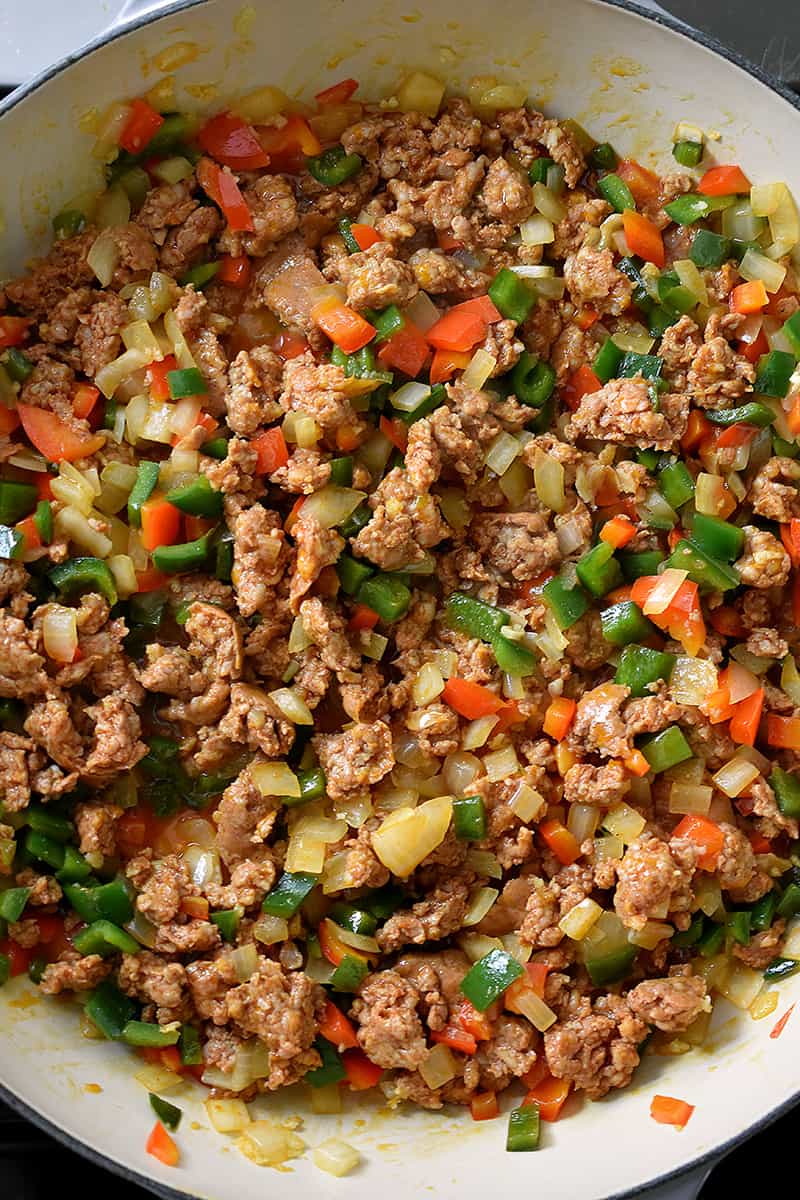 Overhead shot of a pan filled with cooked Mexican chorizo, diced bell peppers, and onions.