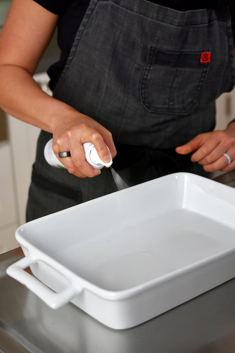 Someone in a gray apron is spraying avocado oil 