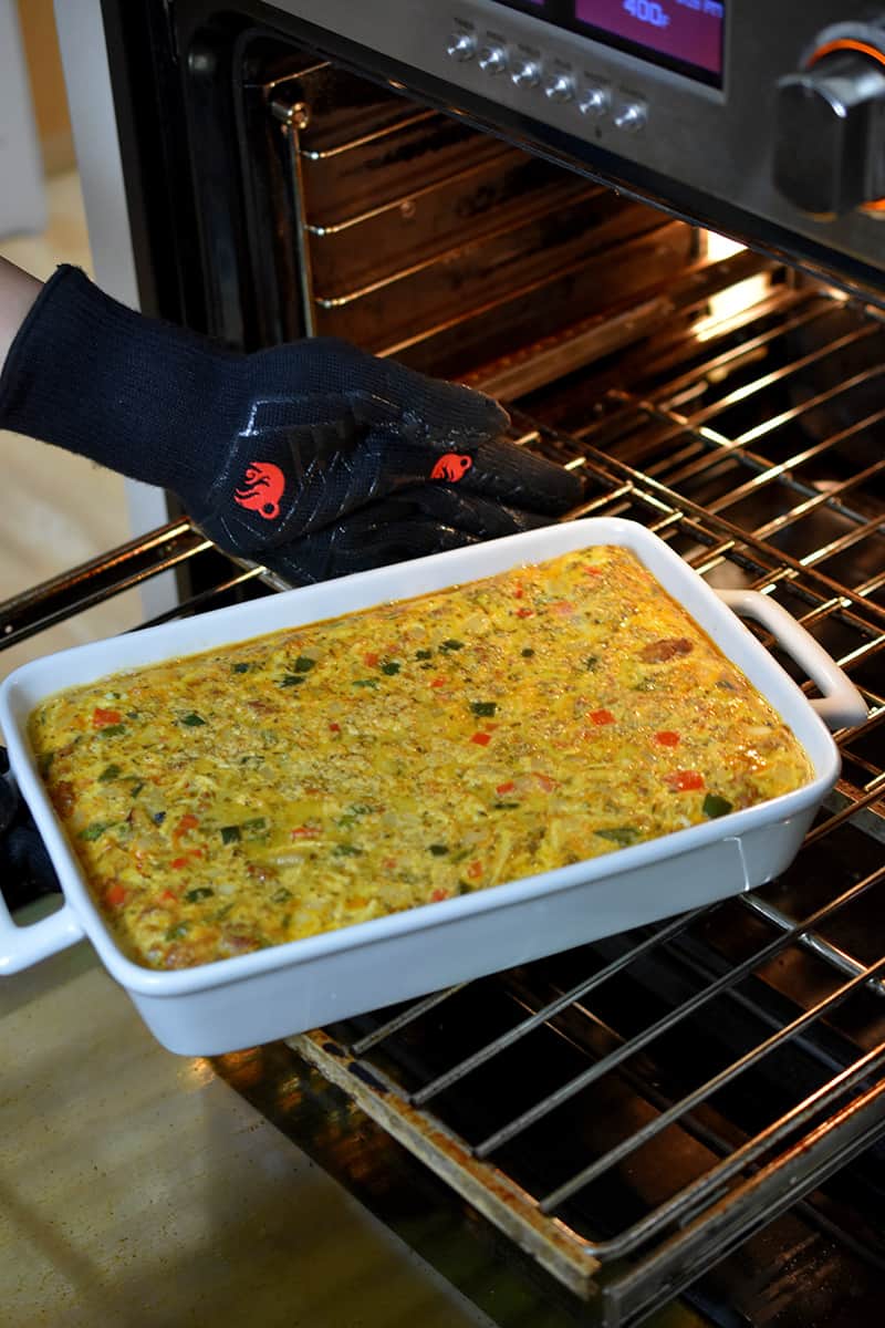 Rotating a white casserole filled with Mexican Breakfast casserole at the midway point during baking.