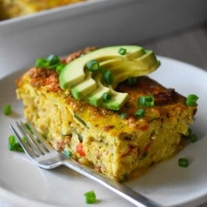 A slice of Mexican Breakfast casserole is on a plate in front of a casserole pan.