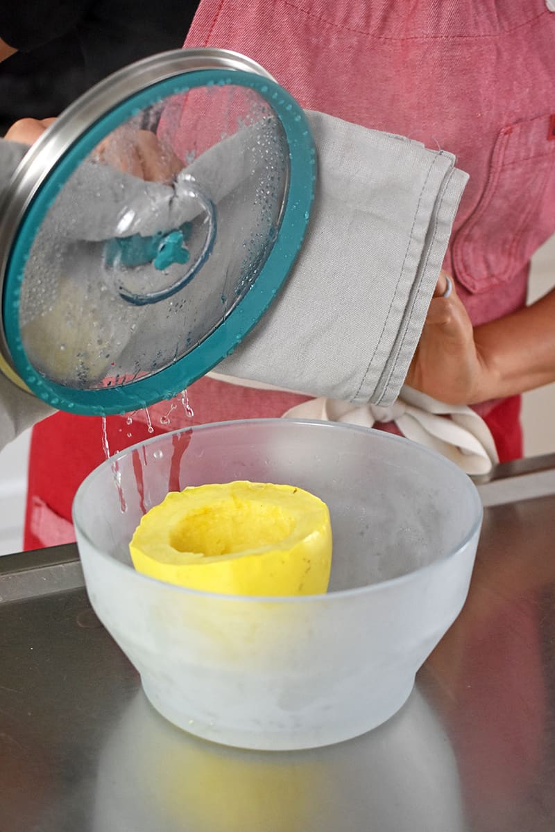 Taking the lid off a glass bowl and checking on the spaghetti squash.