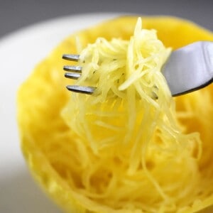 An overhead shot of a fork scooping up microwave spaghetti squash from a cut half.