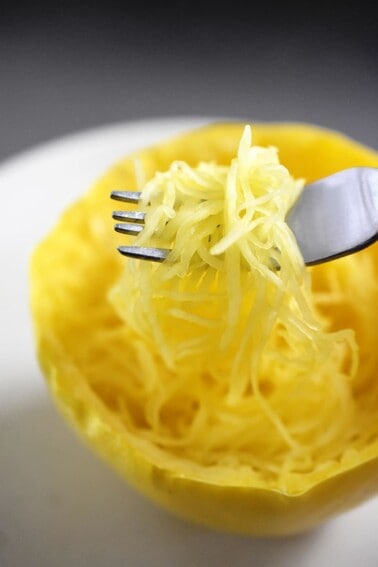 An overhead shot of a fork scooping up microwave spaghetti squash from a cut half.