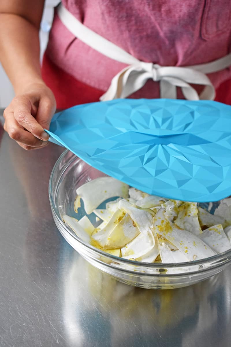 Covering a bowl of king oyster mushroom salad with a blue silicone lid.