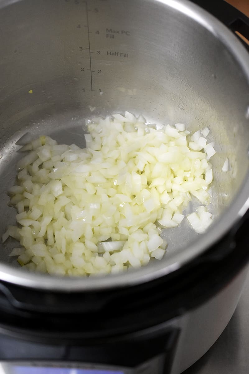 An overhead shot of diced onions being sautéed in an Instant Pot.