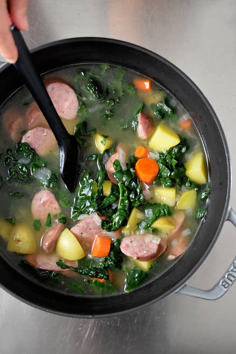 Overhead shot of kale and sausage soup in a pot ready to finish cooking.
