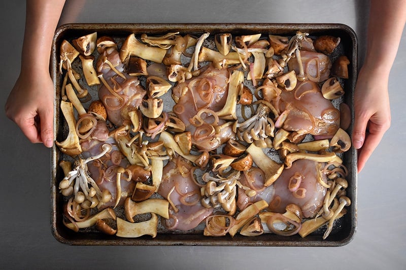 The Sheet Pan Chicken and Mushrooms should be arranged in a single layer before baking.