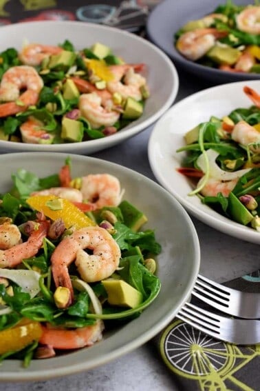 A closeup of four shallow bowls filled with shrimp and avocado salad