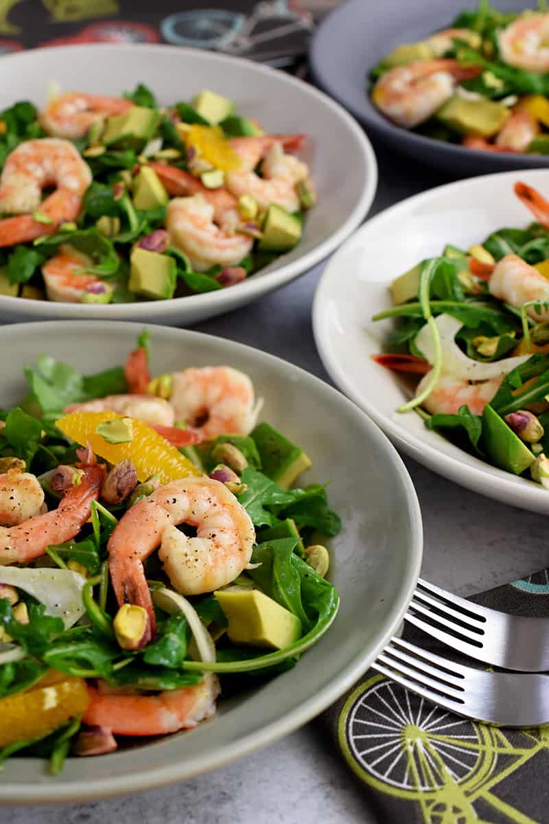 A closeup of four shallow bowls filled with shrimp and avocado salad