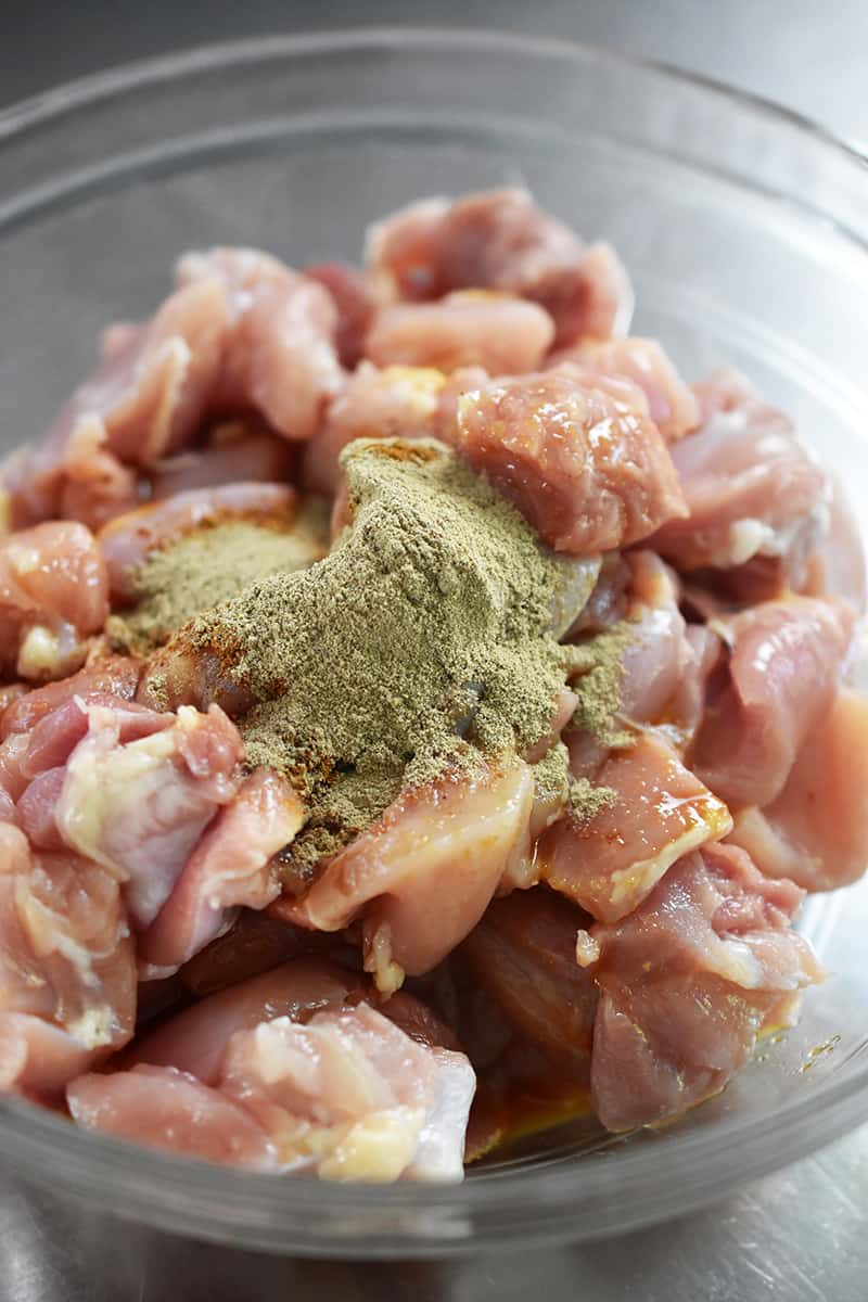 A bowl of cubed, marinated chicken with five spice powder and ground white pepper on top.