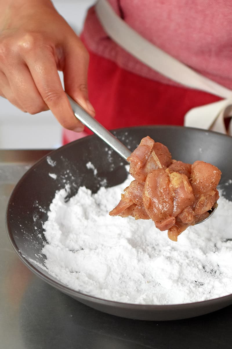 Coating the marinated chicken with potato starch before frying the Taiwanese popcorn chicken.