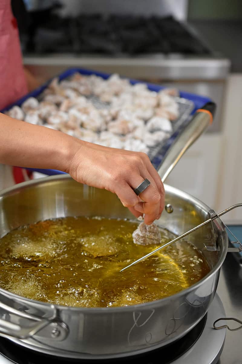 Adding battered chicken bites to hot oil to make Taiwanese popcorn chicken