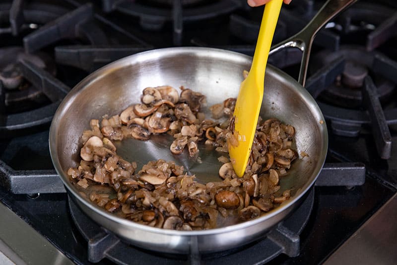 An overhead shot of a stainless steel skillet filled with sautéed mushrooms where the liquid has evaporated.