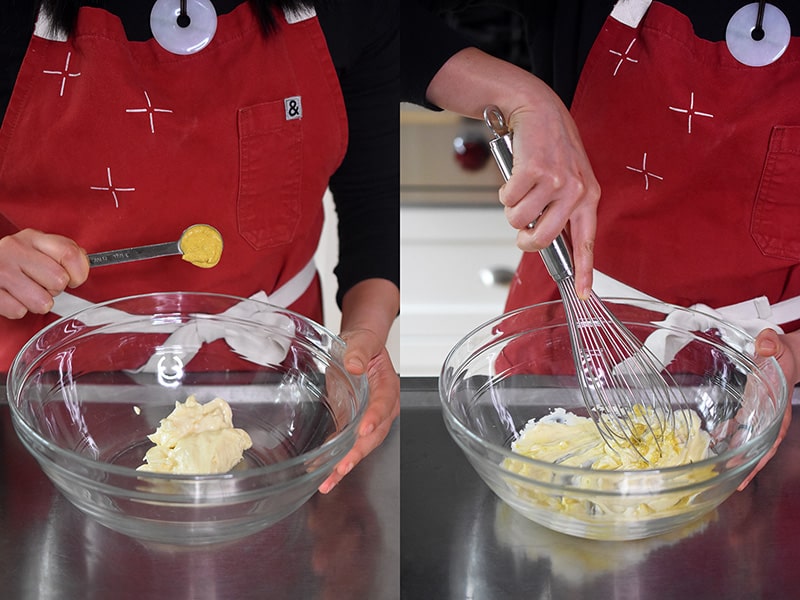 Adding a spoonful of dijon mustard to a bowl of mayonnaise and mixing it with a whisk.