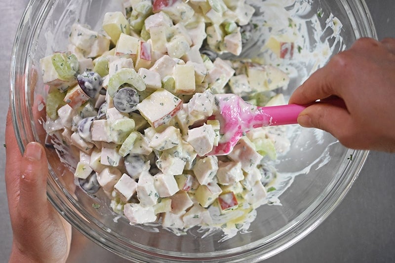 Mixing a chicken waldorf salad in a large bowl.