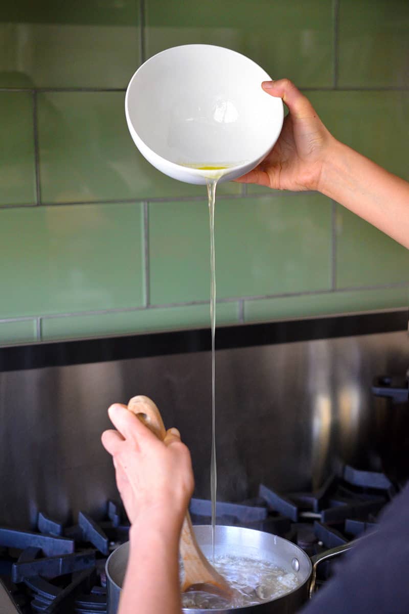 Pouring whisked egg whites into a hot pot of soup.