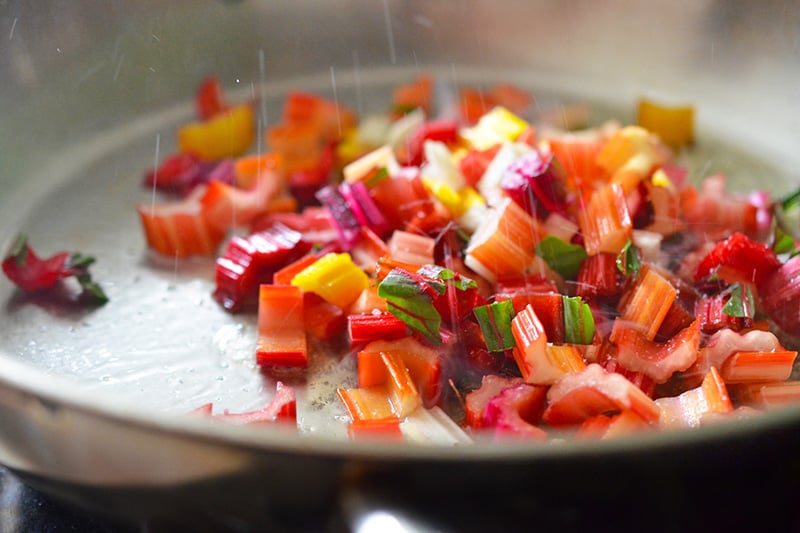 Rainbow chard stems frying in a pan.