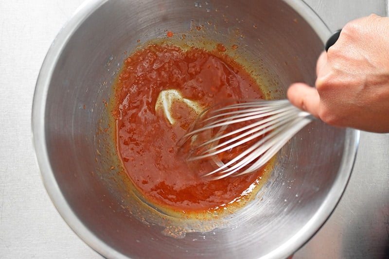Whisking the marinade for Sheet Pan Chicken Fajitas in a large metal bowl.