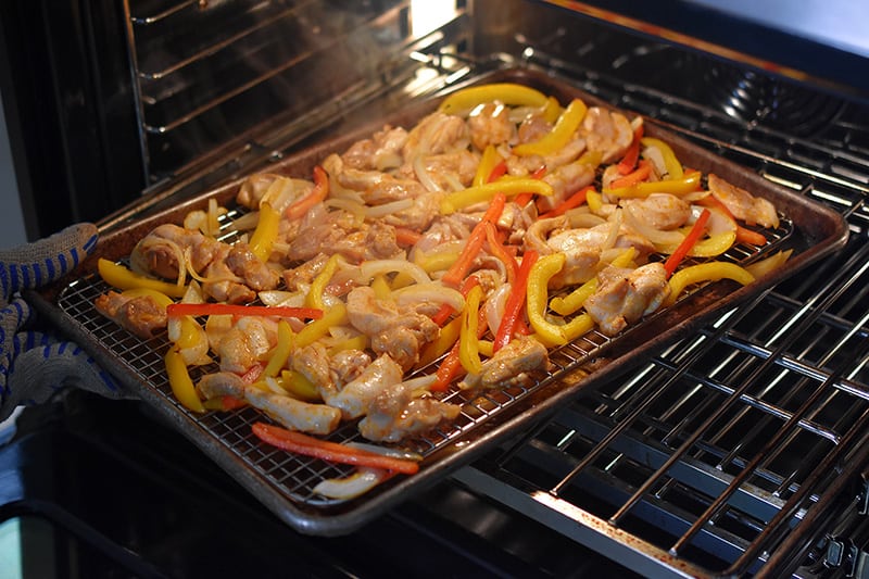 Turning the Sheet Pan Chicken Fajitas 180° at the halfway point of the baking process.