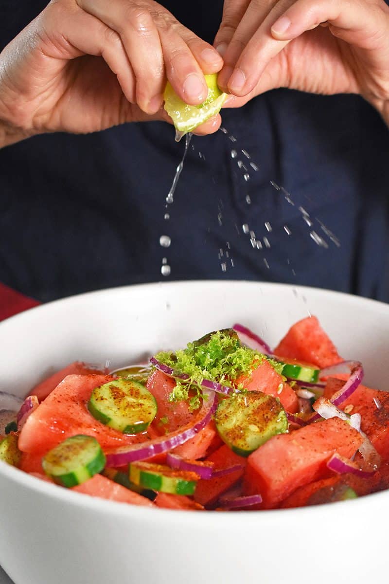 Someone spraying fresh lime juice over the paleo Mexican watermelon salad.