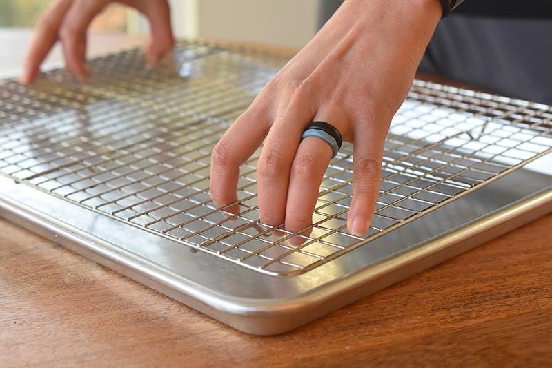 Someone putting a wire rack on top of a baking sheet.